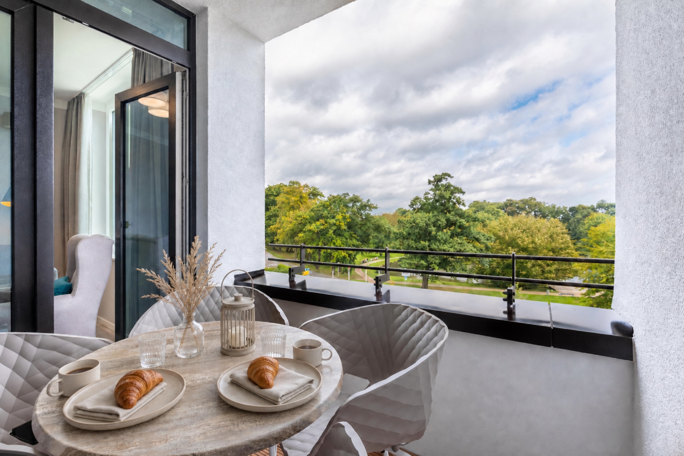 Gedeckter Frühstückstisch auf der Loggia mit Blick in den Park